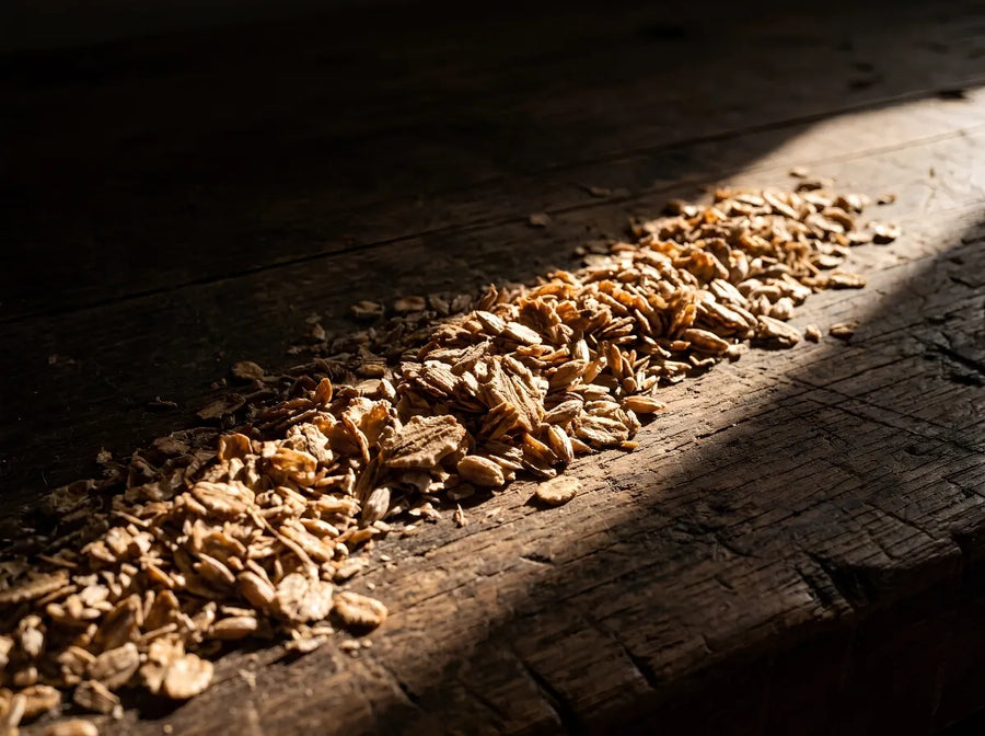 Loose rye bran on weathered timber, lit by a single shaft of daylight